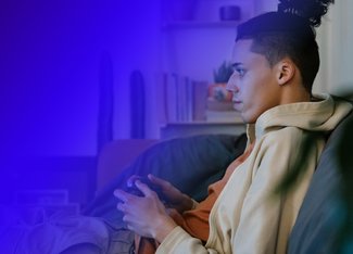 a young man gaming on a couch with a controller