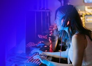 woman wearing a headset plays a PC game at a gaming station