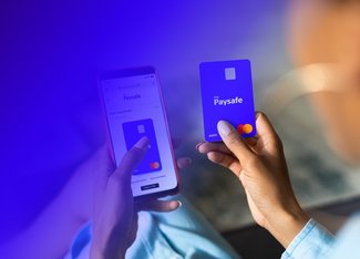 phone showing PaysafeCard application in the left hand and a Debit Mastercard in the right hand
