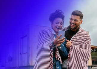 woman and man smiling and looking at a mobile phone 