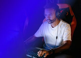 Man staring focused at a laptop screen while wearing headphones