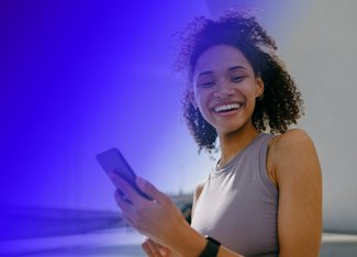 woman holding a phone and looking at the camera smiling brightly