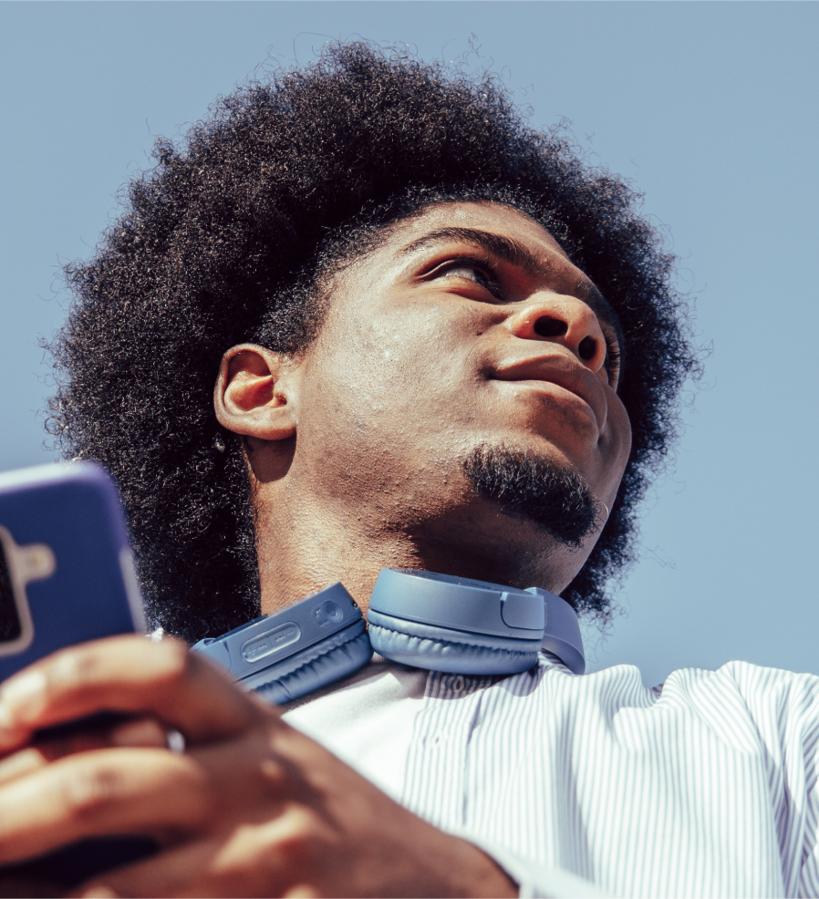 man wearing headphones around neck and holding a phone