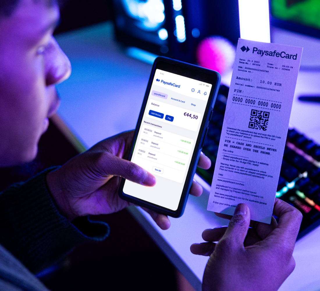 person holding phone showing PaysafeCard application UI and entering details from a PaysafeCard voucher